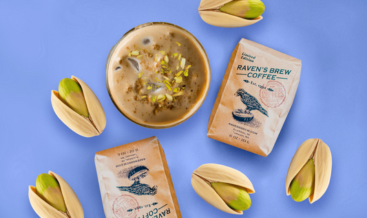 Roaster's Pick Coffee sits amongst giant pistachios and a beautiful frothy cup of Pistachio Cream Cold Brew.