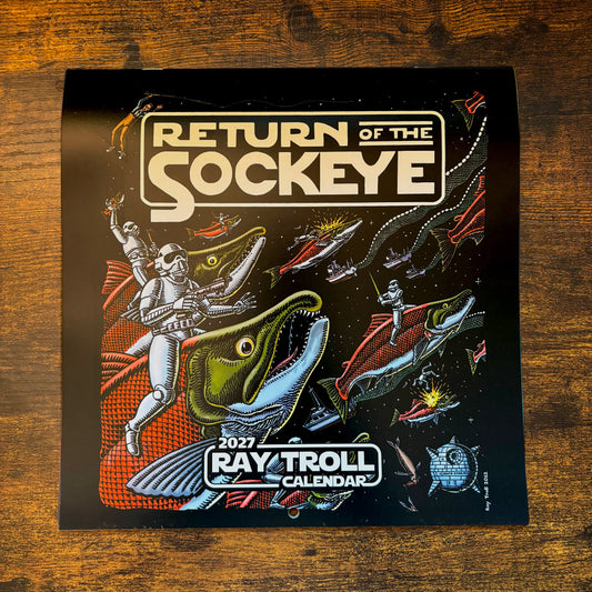 Front of the 2027 Ray Troll Calendar titled "Return of the Sock Eye" laying flat on a wooden table. The illustration on the front features space warriors riding salmon in space, complete with light swords and large planetary weapons.