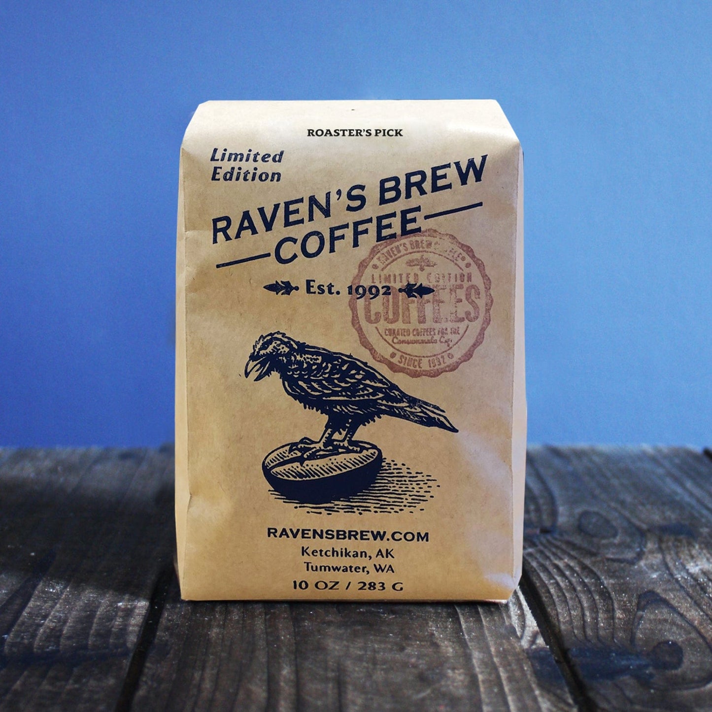 10oz Limited Release Roaster's Pick Coffee bag on a wooden surface with a blue background