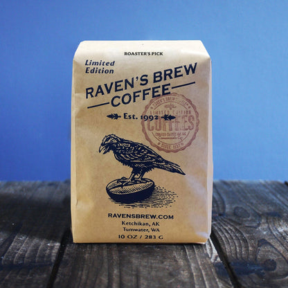 10oz Limited Release Roaster's Pick Coffee bag on a wooden surface with a blue background