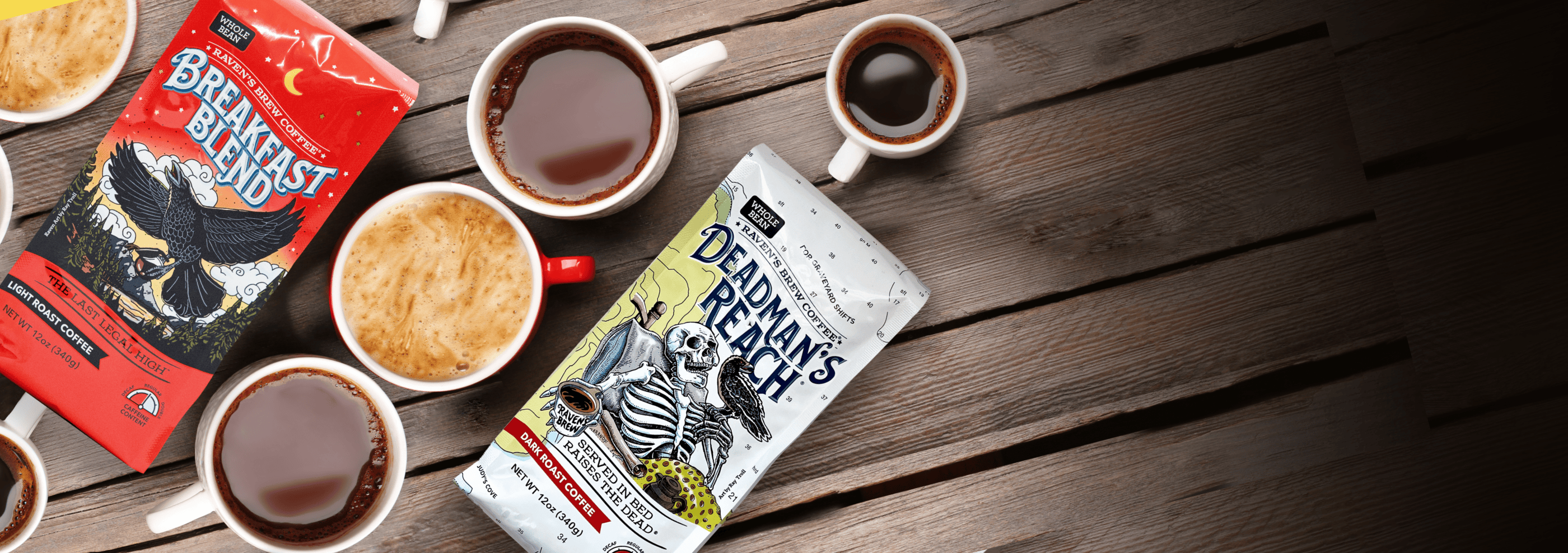 Two coffee product packages and several cups of coffee arranged on a dark wooden tabletop. The packages read Breakfast Blend and Deadman's Reach, with illustrated graphics on the front.