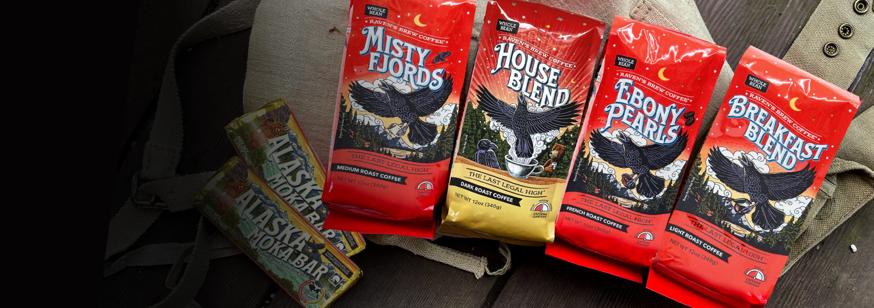 Four Red Raven's Brew Coffee Bags laid on a wooden deck. Choose your adventure!