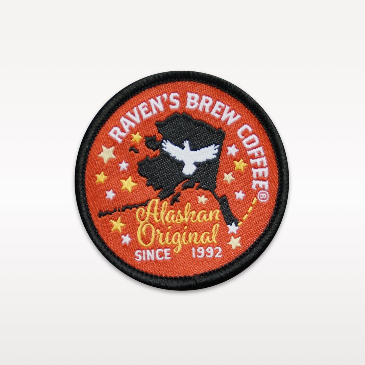 Round Raven's Brew Coffee embroidered patch featuring a raven within a silhouette of Alaska, surrounded by stars, with the words "Alaskan Original Since 1992" emblazoned at the bottom.