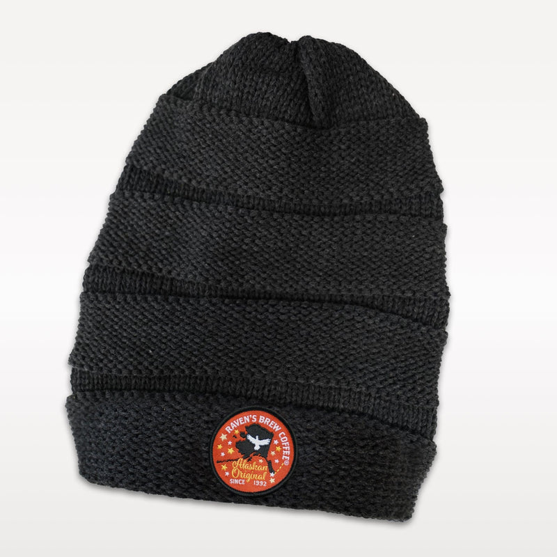 Charcoal knit scrunch beanie featuring a round Raven's Brew Coffee Alaskan Original embroidered patch with a silhouette of Alaska.